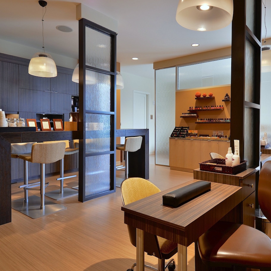 A modern hotel lobby with a wooden reception desk, bar area, and seating.