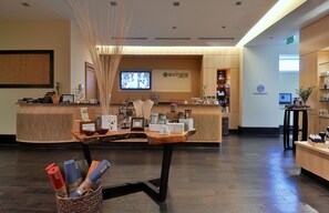 A reception area with a wooden reception desk, a television screen, and a wall-mounted clock.