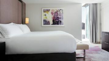 A modern hotel room with a large bed, a bedside table, a lamp, and a window with curtains.