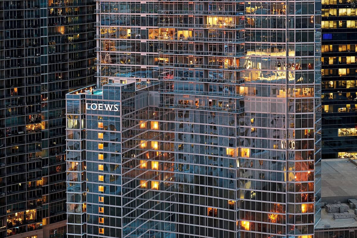 A high-rise building with a glass facade, multiple floors, and a prominent 'LOEWS' sign.