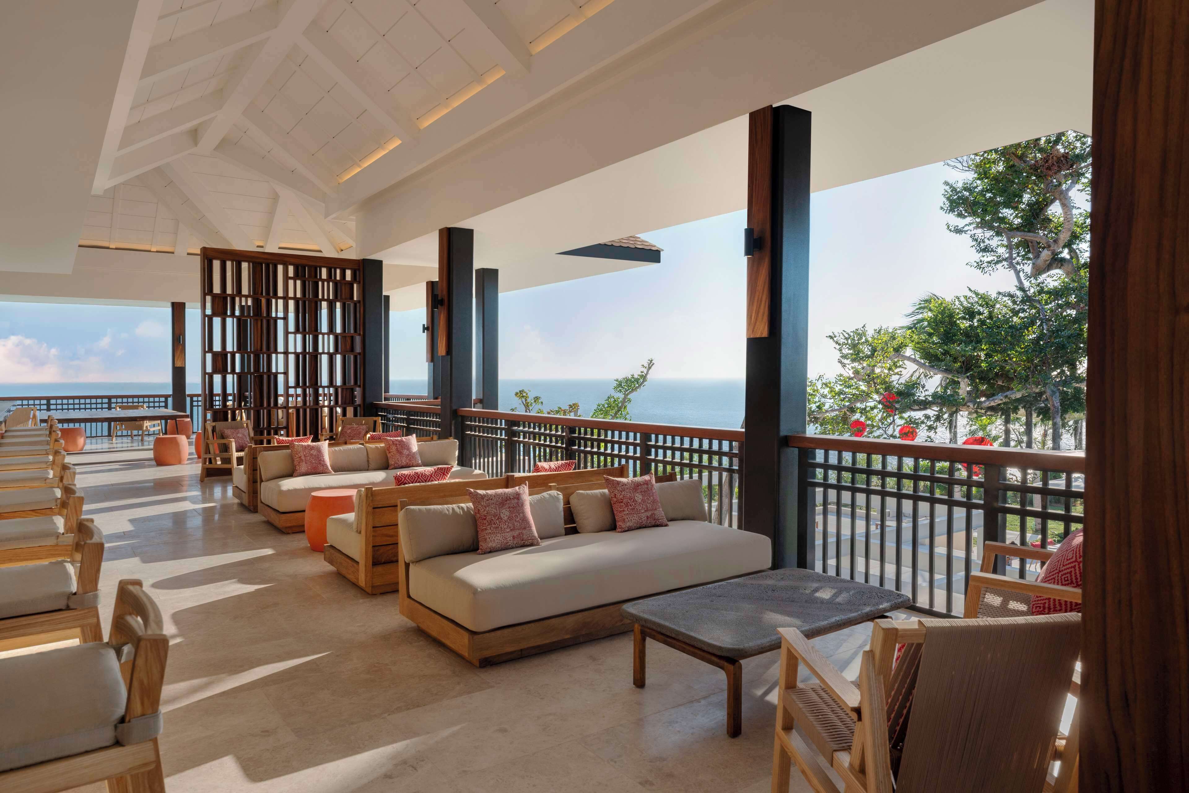 A spacious outdoor seating area with a view of the ocean, wooden furniture, and a modern ceiling design.