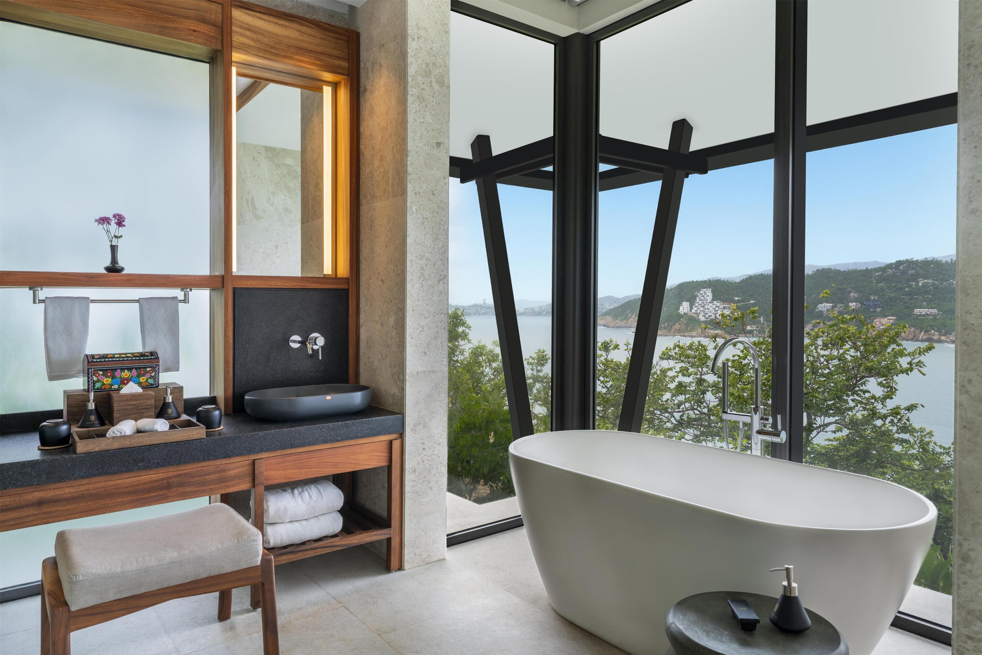 Uma casa de banho moderna com uma banheira independente, um espelho grande e vista para um lago.