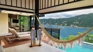A hammock, a pool, and a view of the sea and hills.