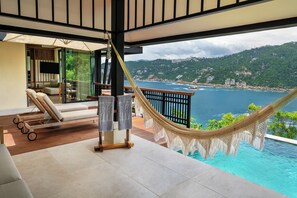 Un hamac, une piscine et une vue sur la mer et les collines.