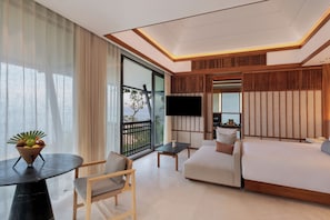 A modern hotel room with a large bed, a sofa, a small table, a TV, and a balcony with a view. - Banyan Tree Cabo Marques (Acapulco)