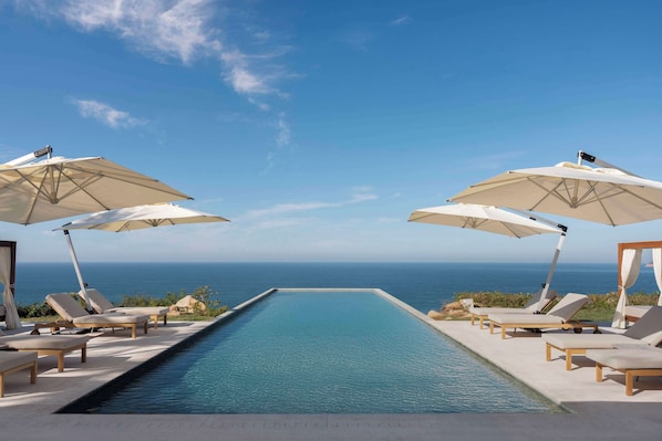 Una piscina al aire libre, camas de piscina gratis, sombrillas