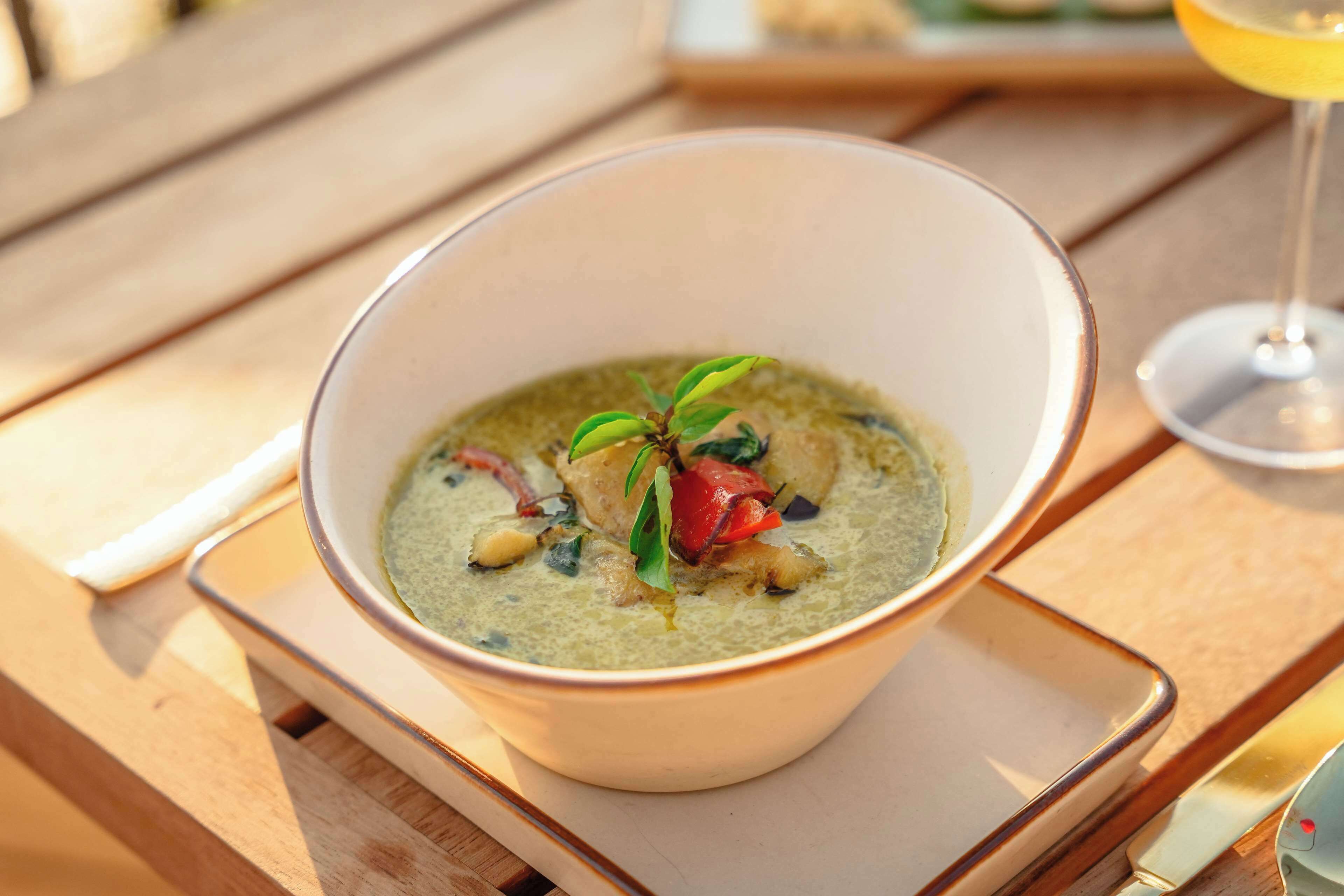 A bowl of soup with a garnish on a wooden table.