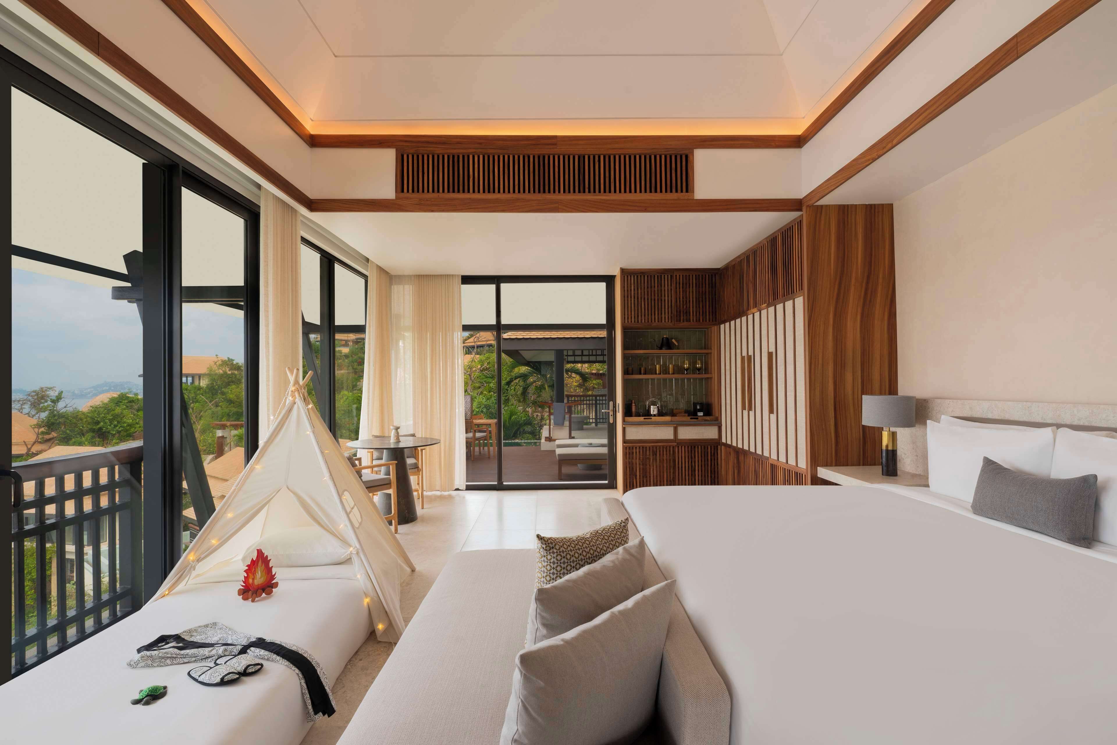 Een moderne hotelkamer met een groot bed, een bank, een zithoek en uitzicht op het omliggende landschap.