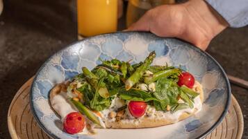A plate of food on a table with a glass of orange juice and a cup of coffee in the background.
