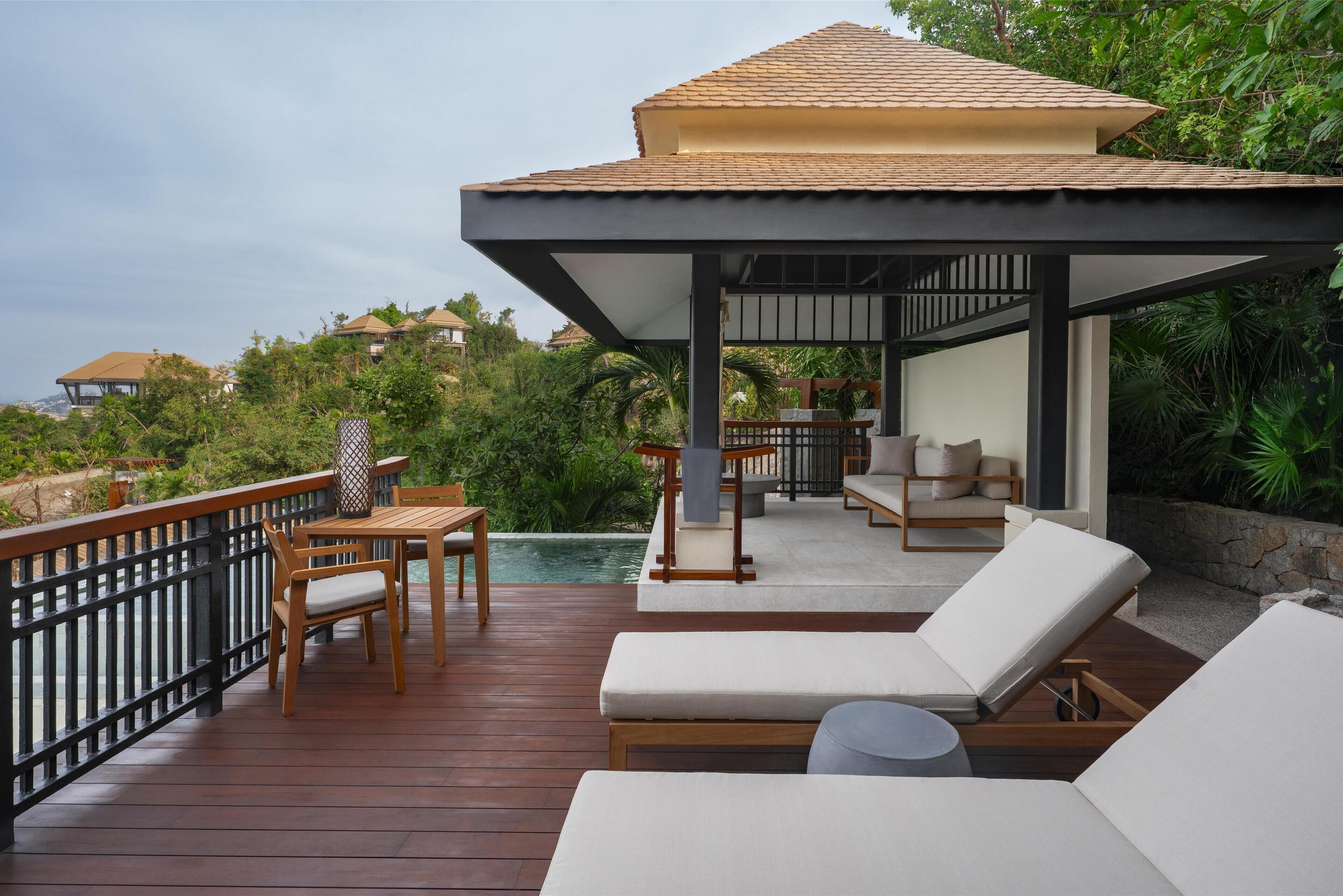 A wooden deck with a covered seating area, a pool, and lounge chairs.