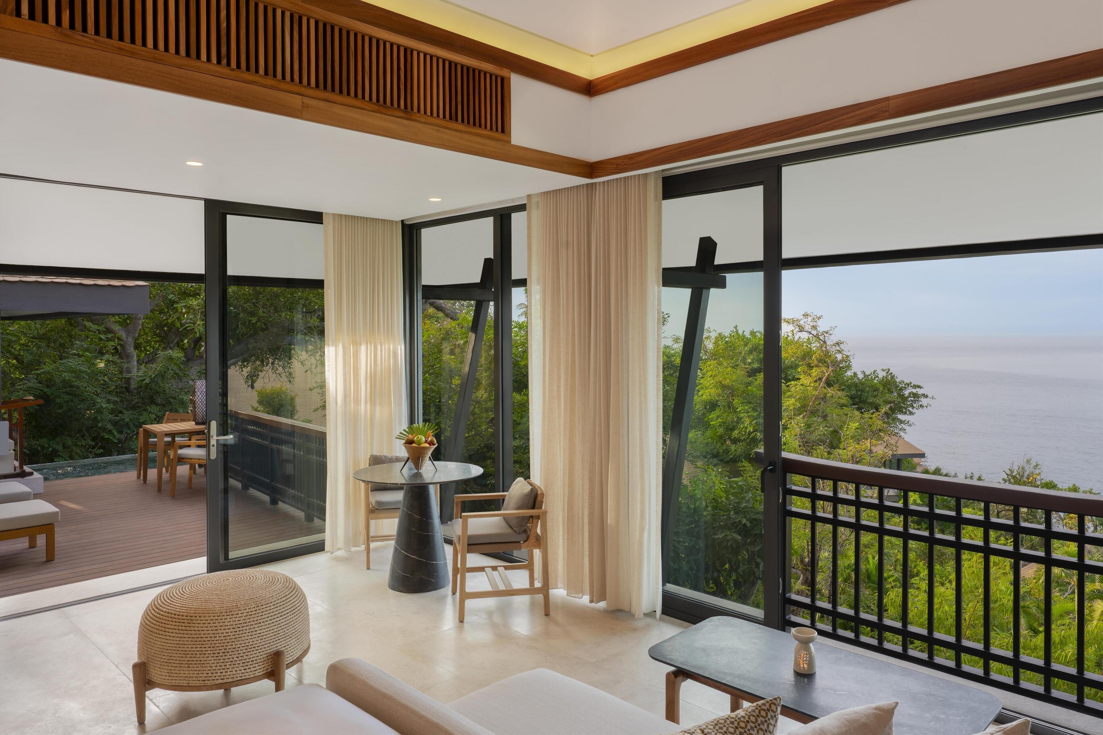 A spacious balcony with a view of the sea, furnished with a sofa, chairs, and a table.