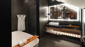 A modern bathroom with a freestanding bathtub, a vanity with a mirror, and a shower area.