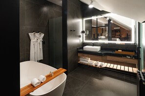 A modern bathroom with a freestanding bathtub, a vanity with a mirror, and a shower area. - Bavaria Sport Hotel (Gramado)