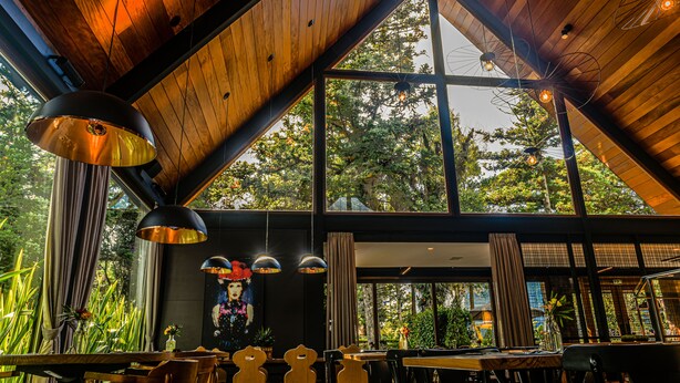A restaurant with wooden ceiling beams, large windows, and hanging pendant lights. - Bavaria Sport Hotel (Gramado)