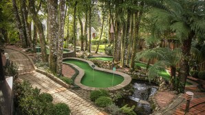 A golf course with a pond, surrounded by trees and a brick pathway. - Bavaria Sport Hotel (Gramado)