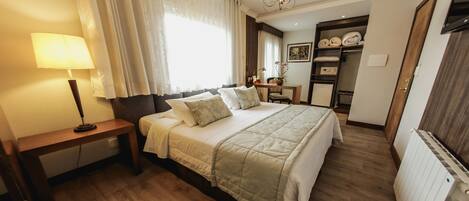 A bedroom with a bed, bedside table, lamp, and a view of a bathroom with a shower and toilet.