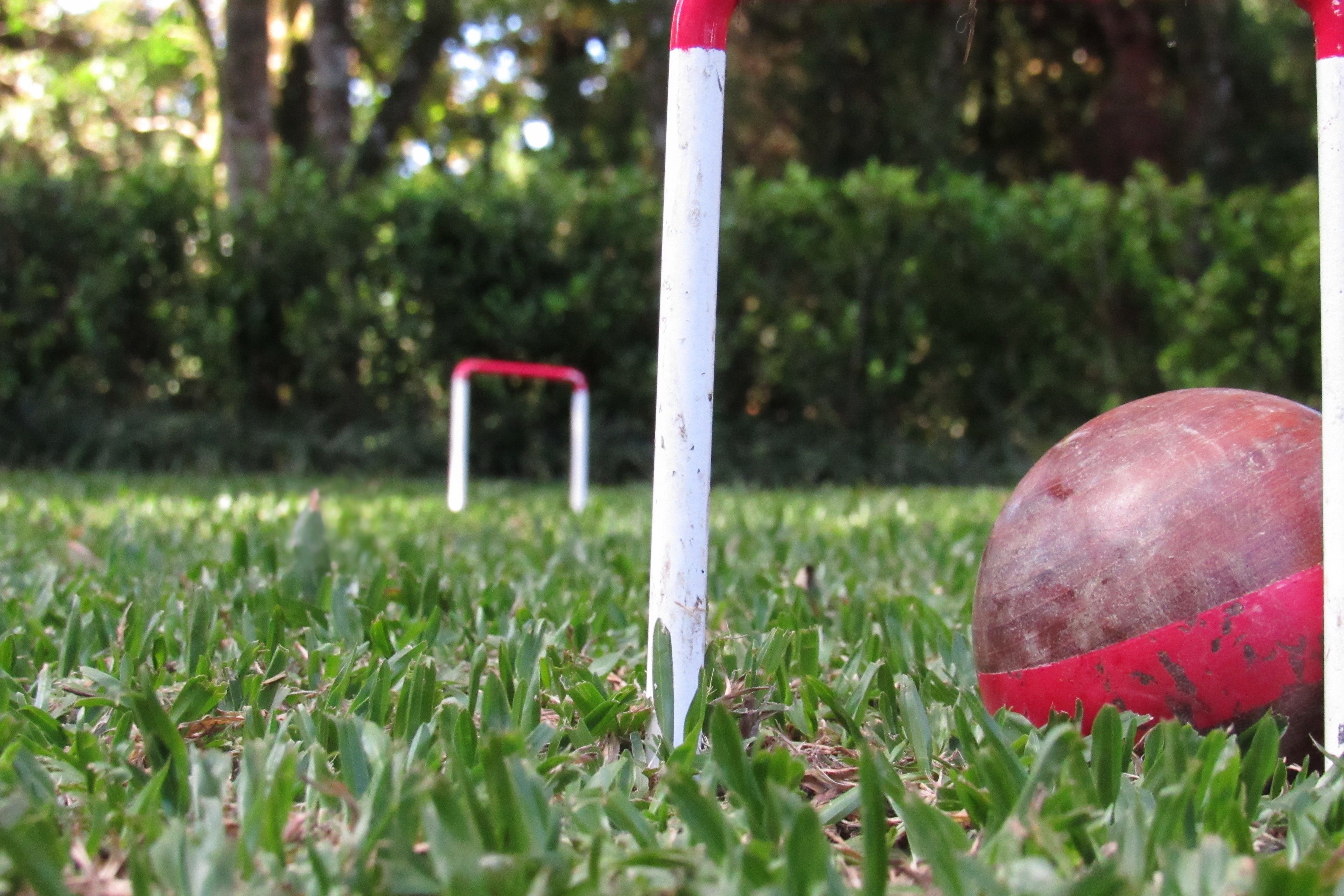 Un campo de golf con un marcador blanco y una pelota roja sobre el césped.