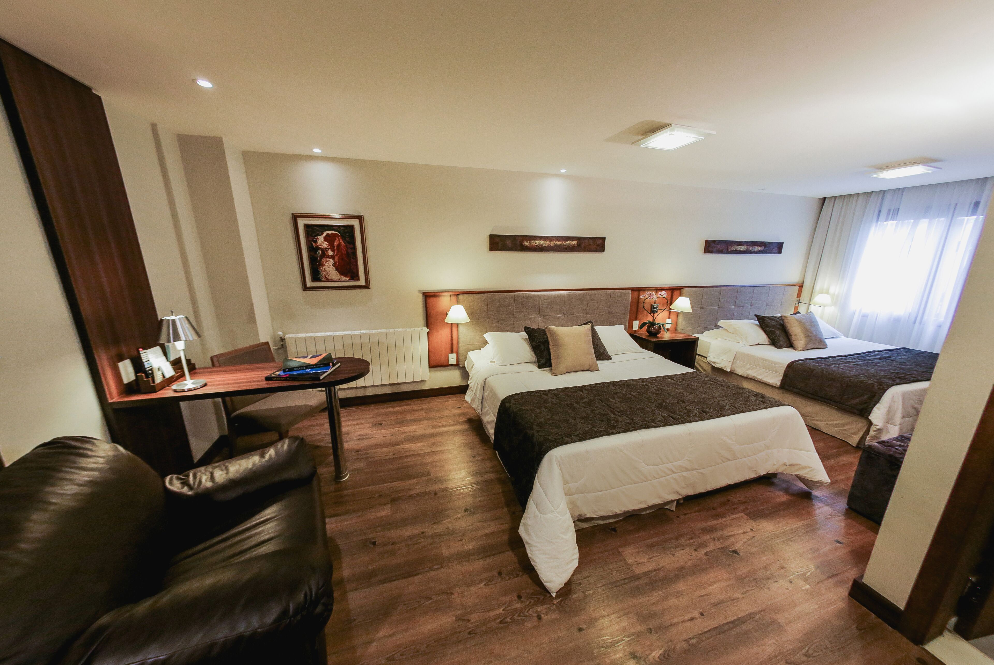 Habitación de hotel con dos camas, un escritorio, una silla y una lámpara.