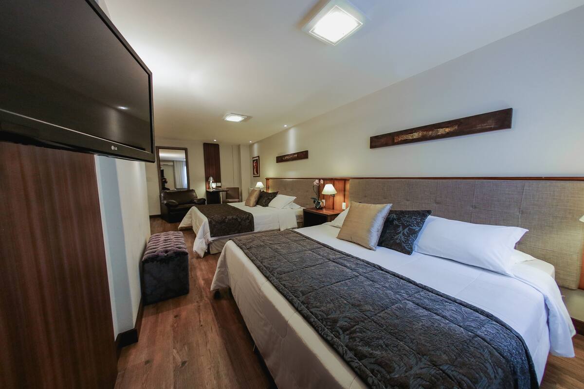 A hotel room with a large bed, a smaller bed, a desk, and a wardrobe.