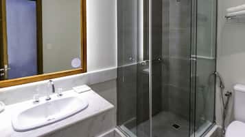 Un baño moderno con ducha envuelta en vidrio, un lavamanos blanco y un espejo grande.