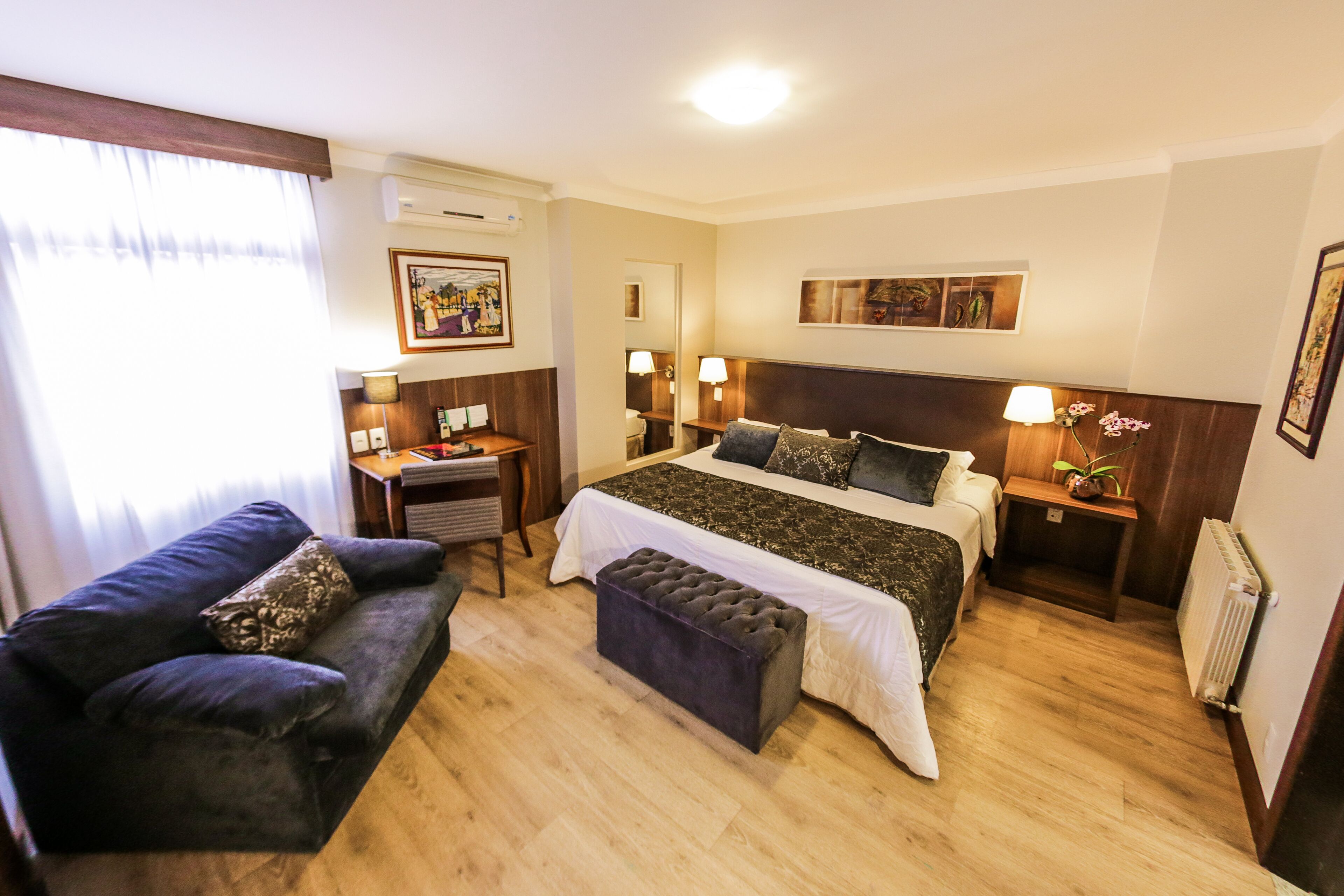 A hotel room with a bed, a sofa, a desk, and a nightstand.