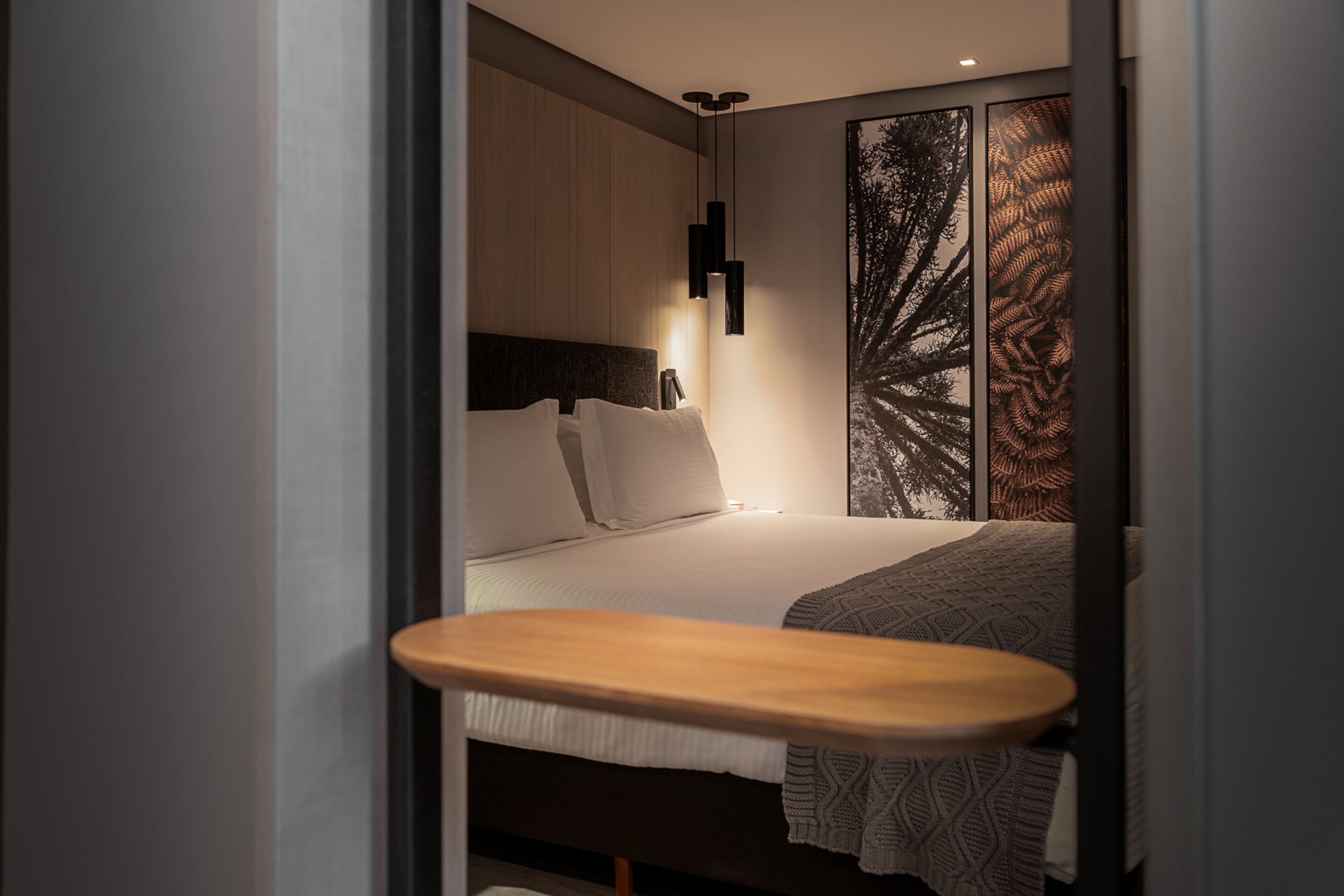 Un dormitorio moderno con una cama, una mesita de noche y una lámpara fijada a la pared.