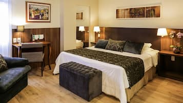 Una habitación de hotel con una cama grande, un escritorio, una silla y una mesita.