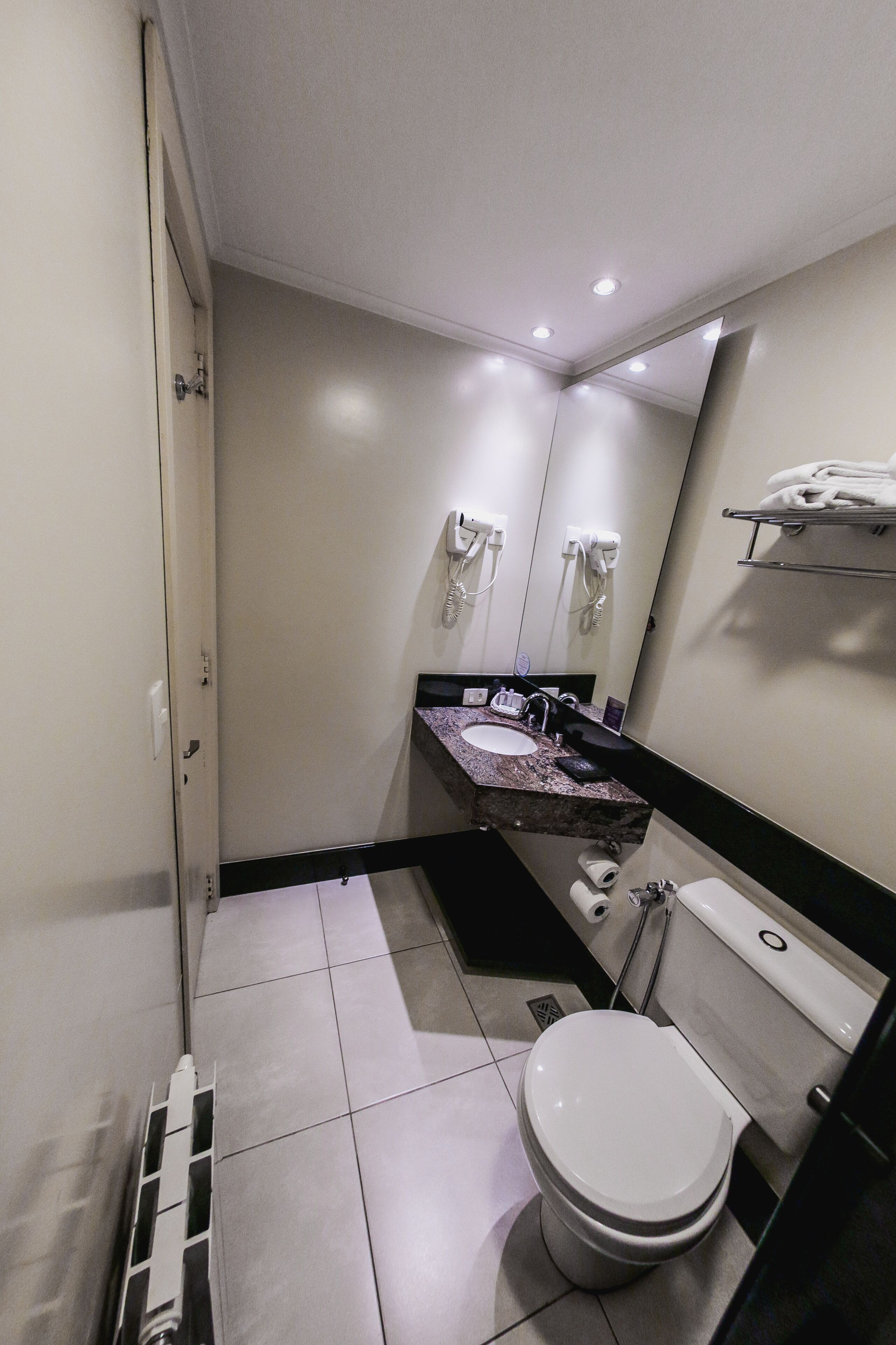 Un baño moderno con inodoro, lavamanos y espejo.