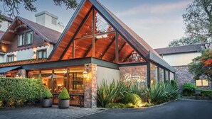A modern hotel with a prominent triangular roof, large glass windows, and a well-maintained garden area. - Bavaria Sport Hotel (Gramado)