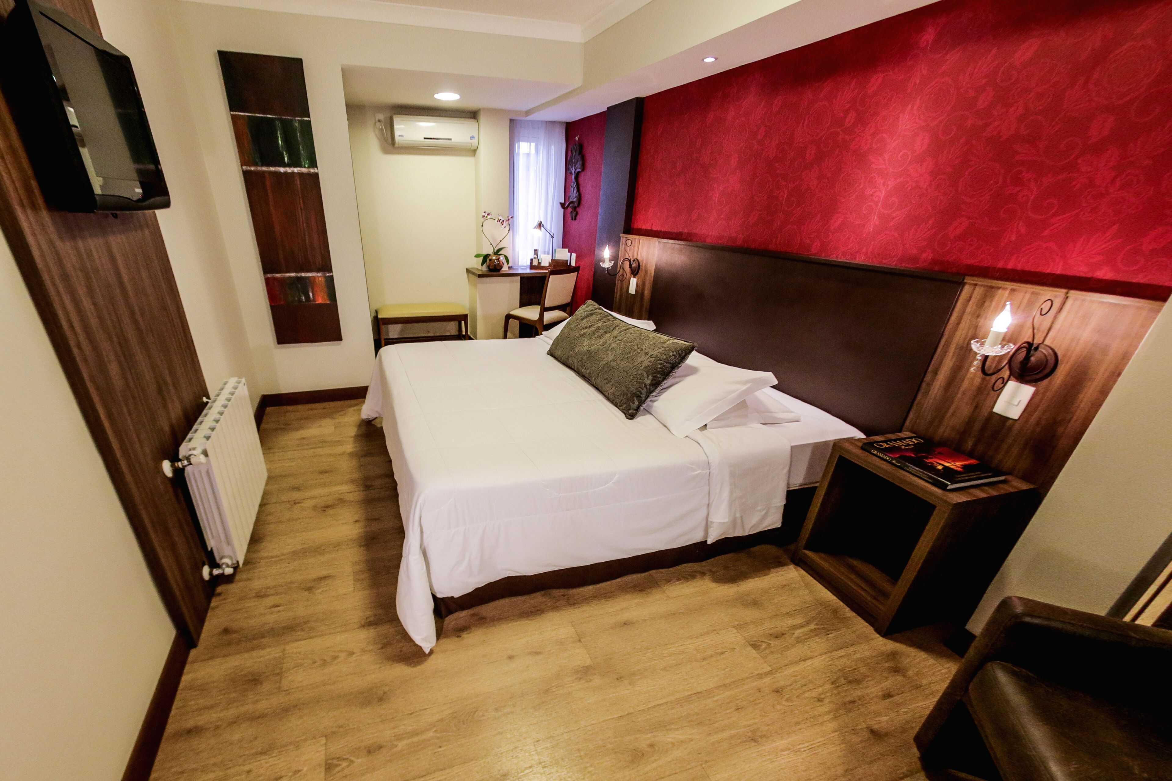 A hotel room with a bed, a desk, and a chair.