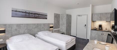 Une chambre d’hôtel moderne avec deux lits, une petite kitchenette et un coin repas.