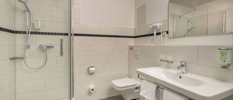A modern bathroom with a glass-enclosed shower, a white toilet, and a sink with a mirror above it.