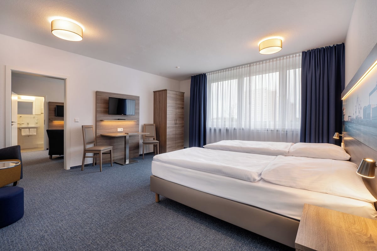 Una habitación de hotel con una cama grande, un escritorio, una silla y un televisor.
