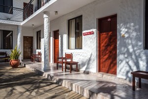 Un edificio con fachada blanca, varias puertas de madera y un cartel que indica las habitaciones 102 a 104.