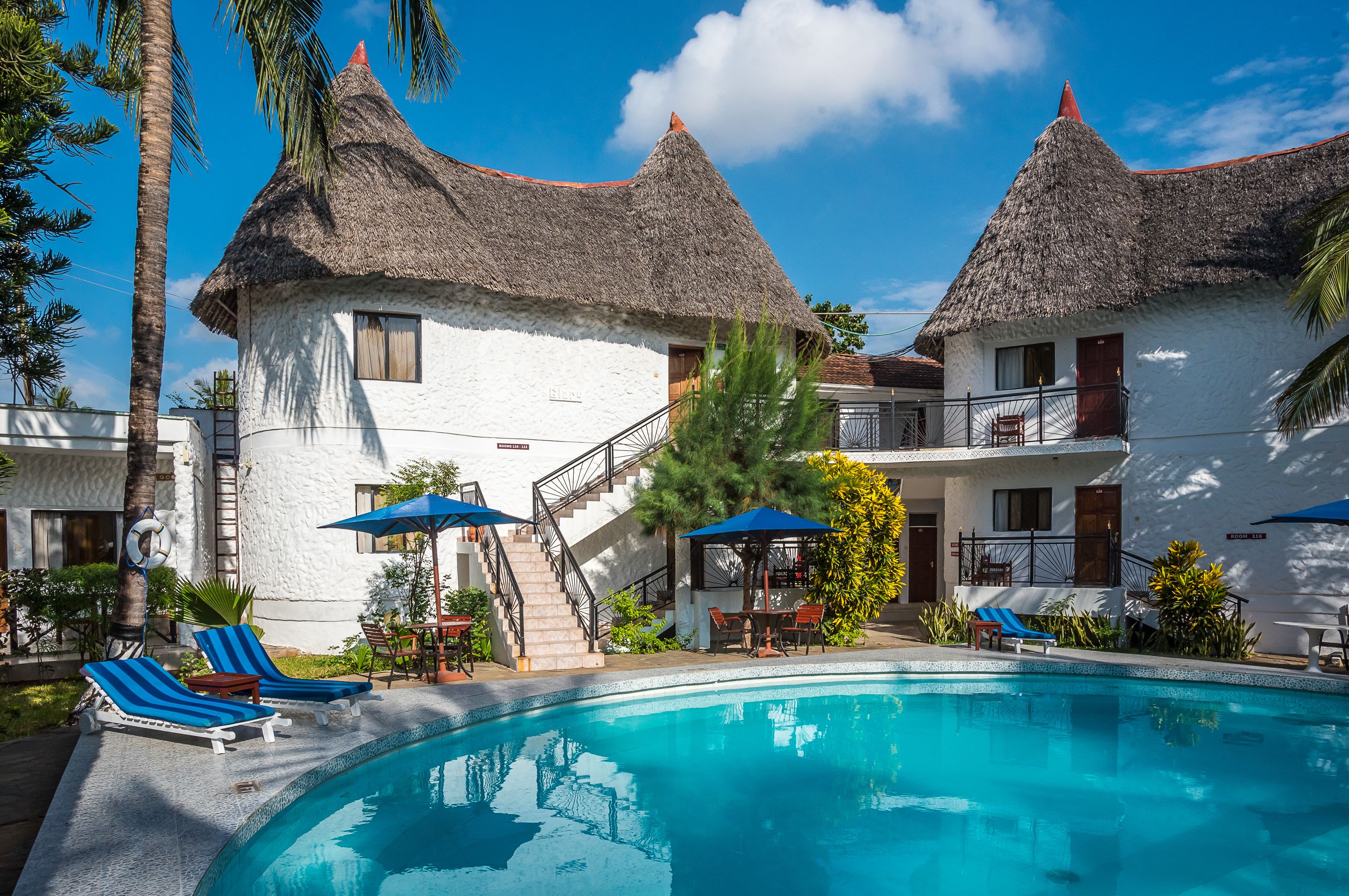A resort with a pool, thatched-roof buildings, and lounge chairs.