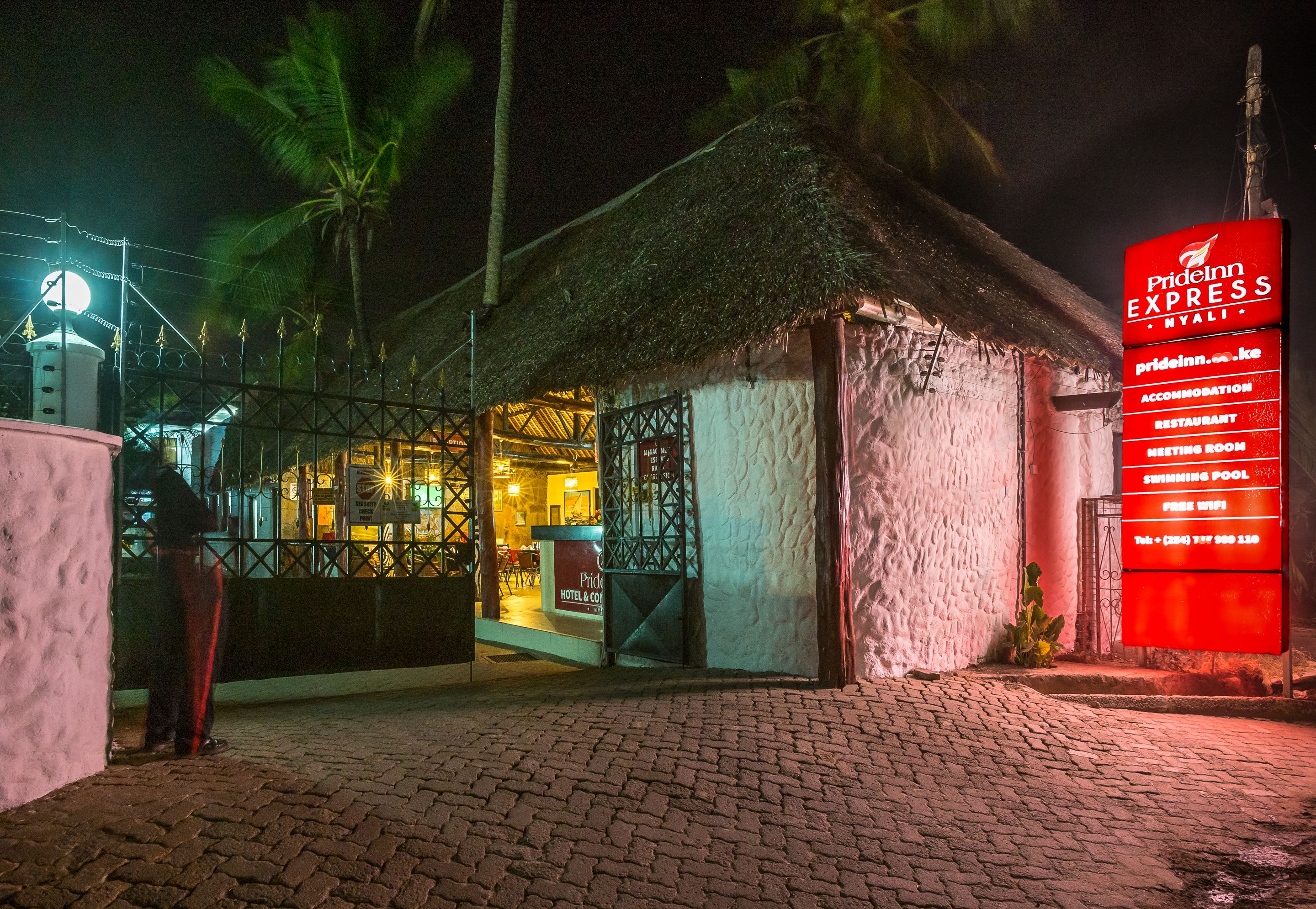 A small, thatched-roof building with a sign for 'Pridelinn Express MYALI' indicating it is a hotel.