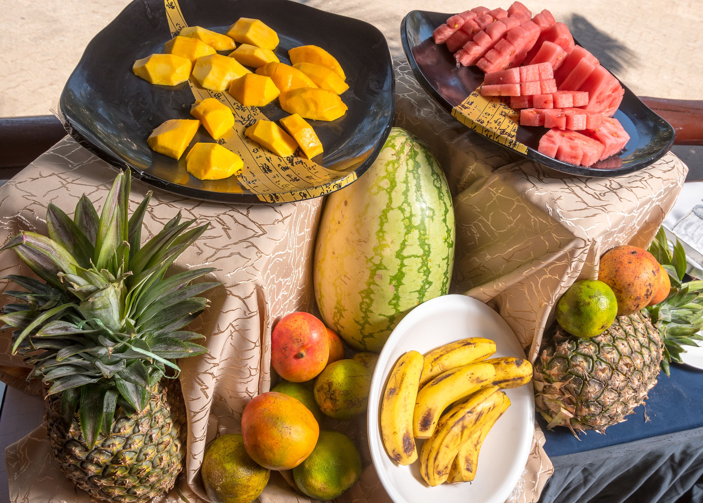 A table with various fruits including pineapple, mango, watermelon, and bananas.