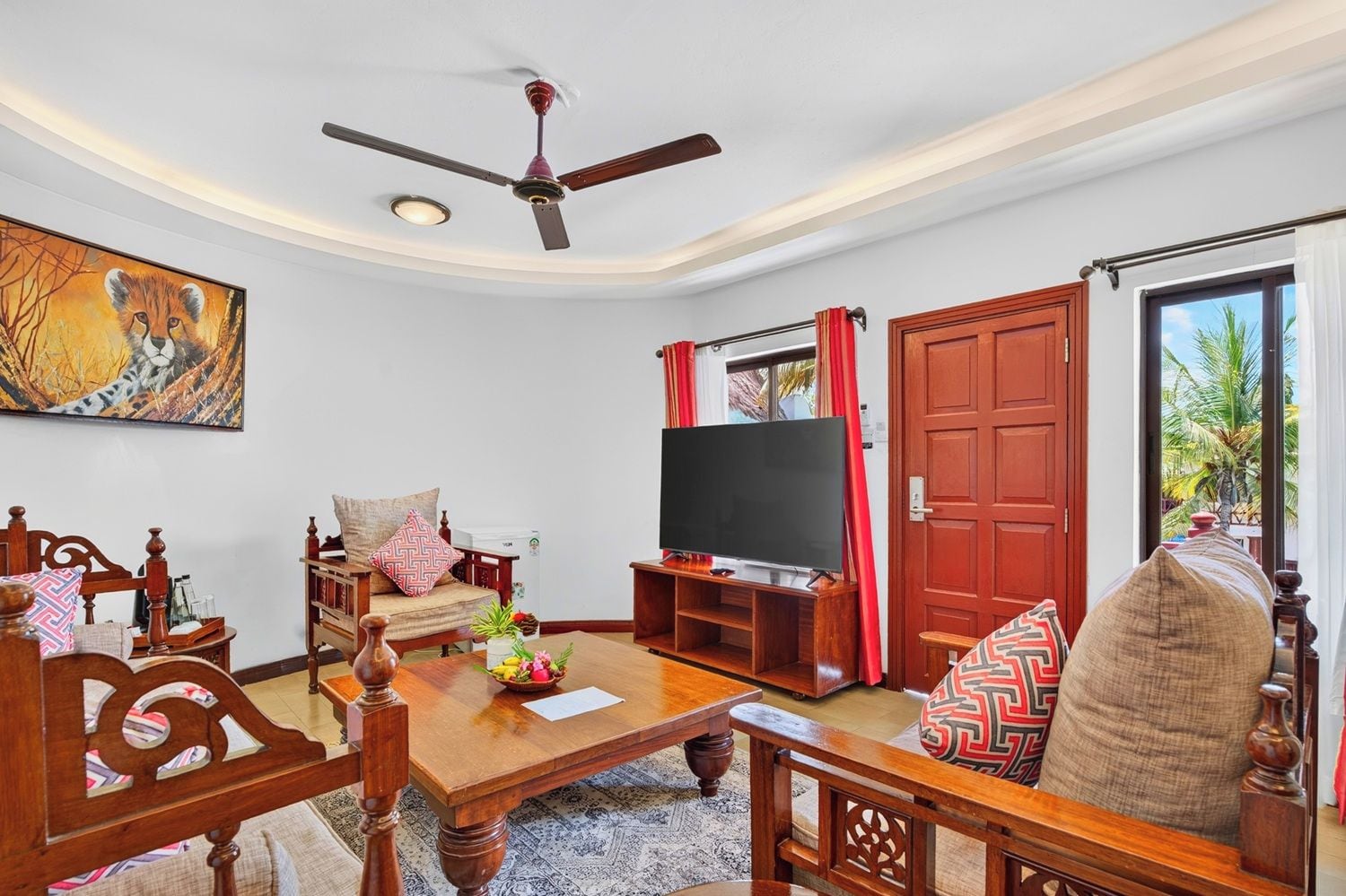 Una sala de estar con un sofá, televisión y ventilador de techo.