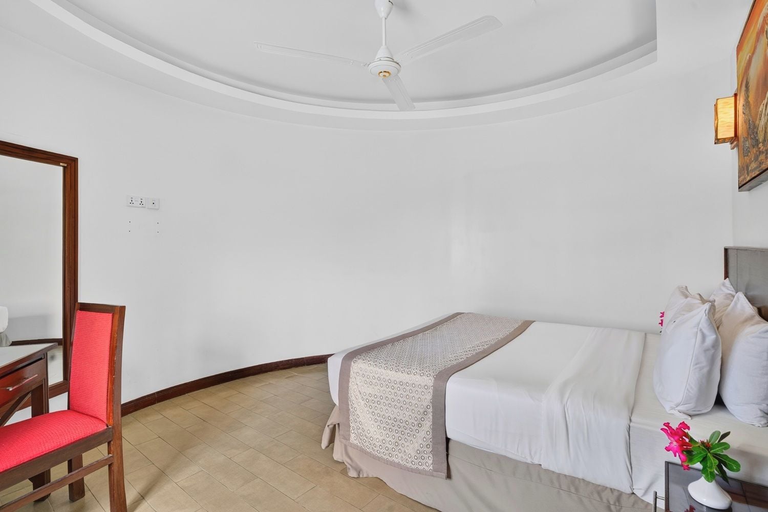 Una habitación de hotel con una cama, una silla, una mesa y un ventilador de techo.