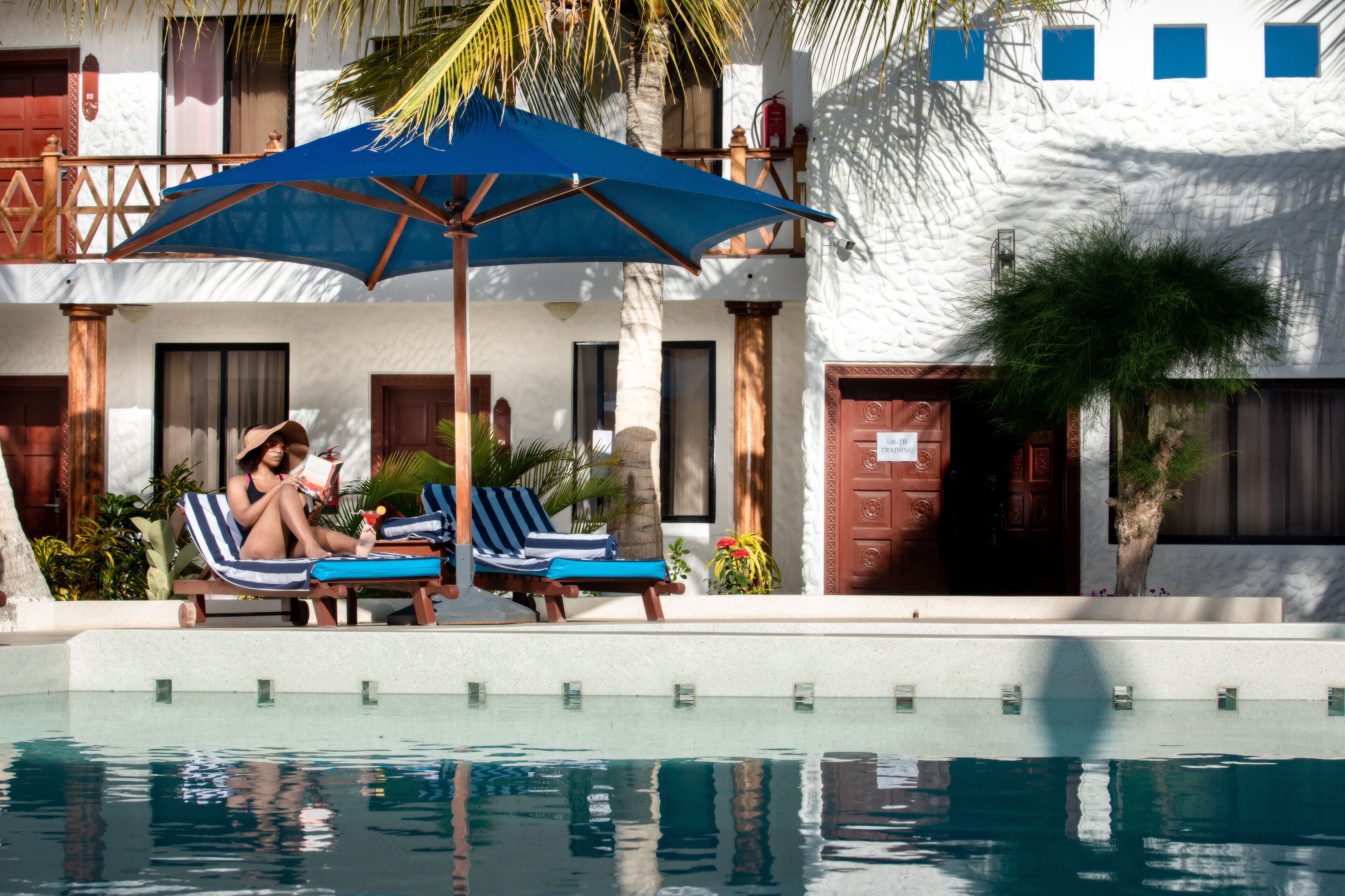 A poolside area with lounge chairs and a blue umbrella.