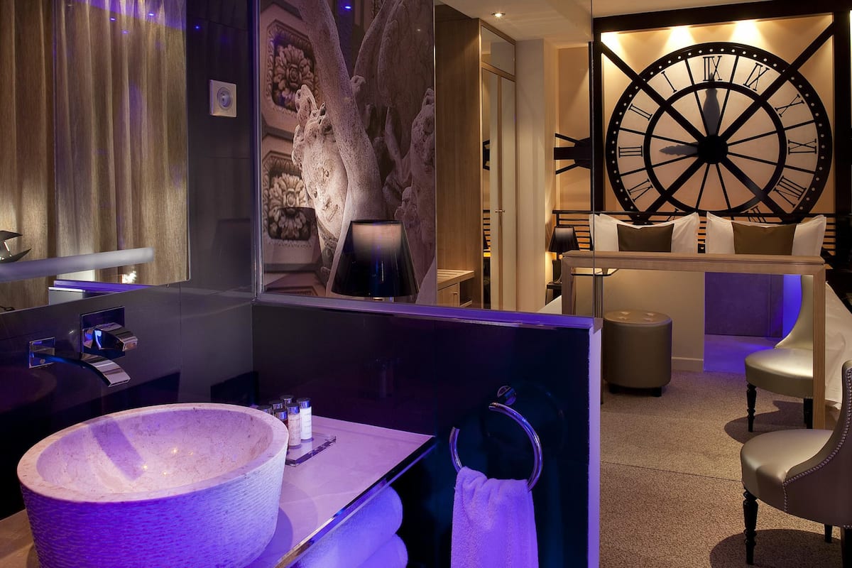 Un baño moderno con un espejo grande, un lavabo de piedra y un reloj de pared grande.