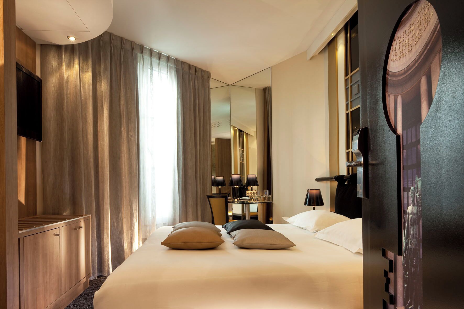 A hotel room with a large bed, a desk with a chair, a TV, and a mirror.