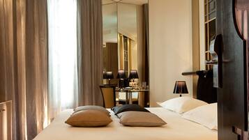 A hotel room with a bed, a desk, a chair, and a mirror.