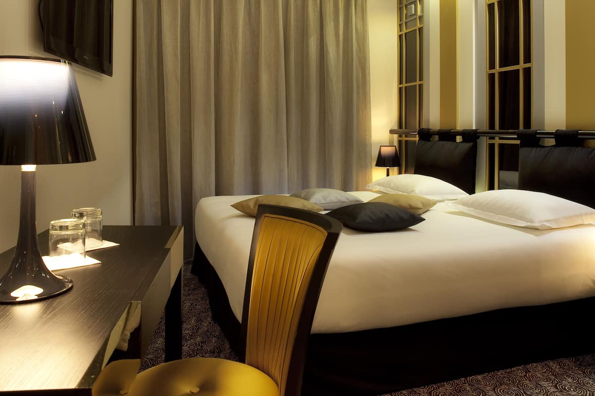 Une chambre d’hôtel avec un lit, un bureau doté d’une lampe et une chaise.
