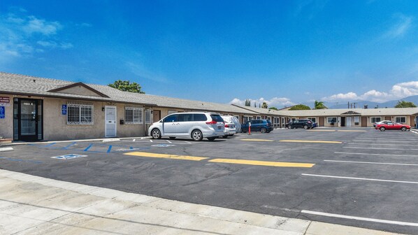A motel with multiple parking spaces, a wheelchair-accessible entrance, and a clear view of the surrounding area. - Sunset Motel (Pomona)
