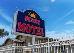 Placa de motel com design de sol e a inscrição 'Sunset Motel'.