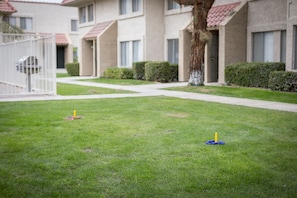 A residential area with a well-maintained lawn, a white gate, and a row of beige apartment buildings with red-tiled roofs. - Indian Palms Vacation Club (Indio)