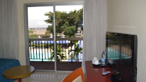 A hotel room with a balcony, a TV, a small table, and a chair. - Hôtel SAWA (Douala)