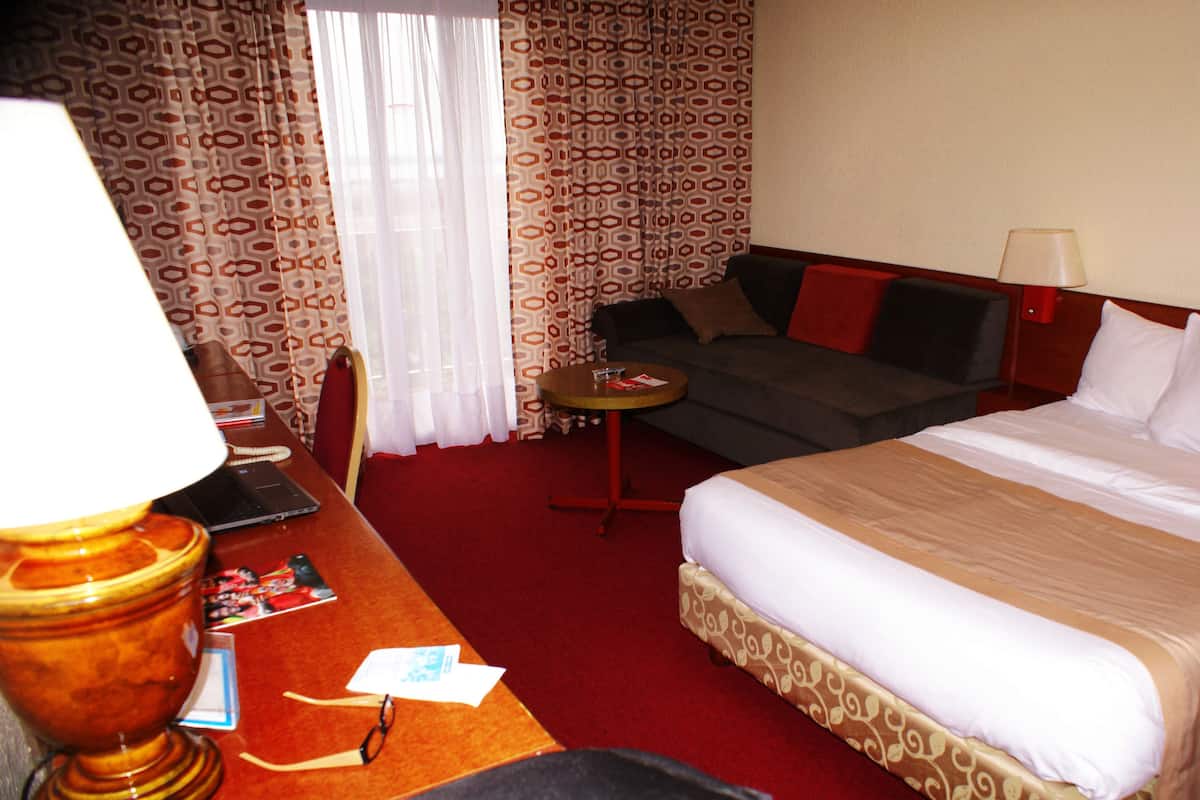 Ein Hotelzimmer mit einem Bett, einer Couch, einem Schreibtisch mit Lampe und einem kleinen Tisch.
