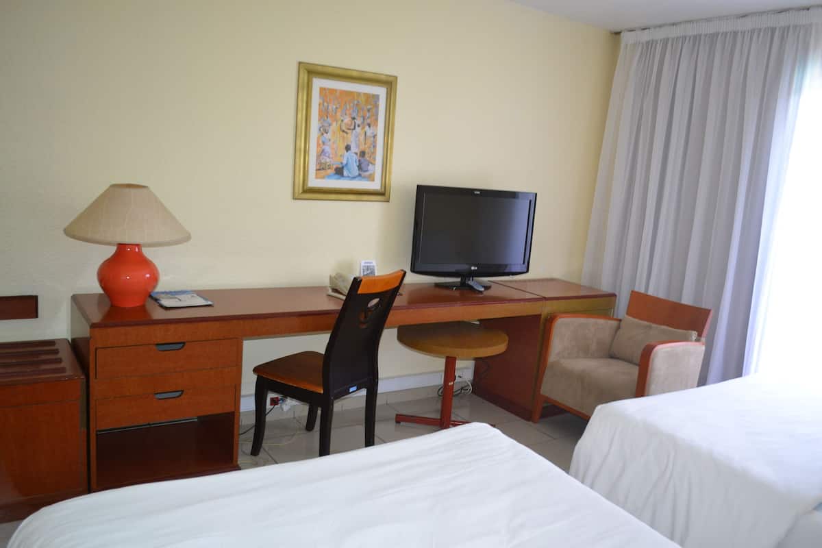 Ein Hotelzimmer mit Schreibtisch, zwei Stühlen, einem Bett und einem Fernseher.